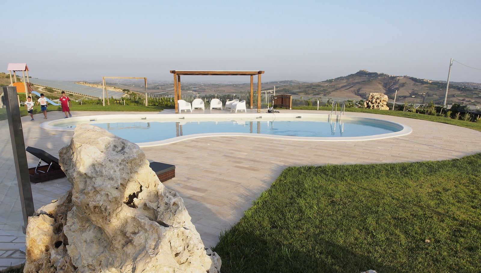 Piscina a fagiolo con pergolato e area giochi