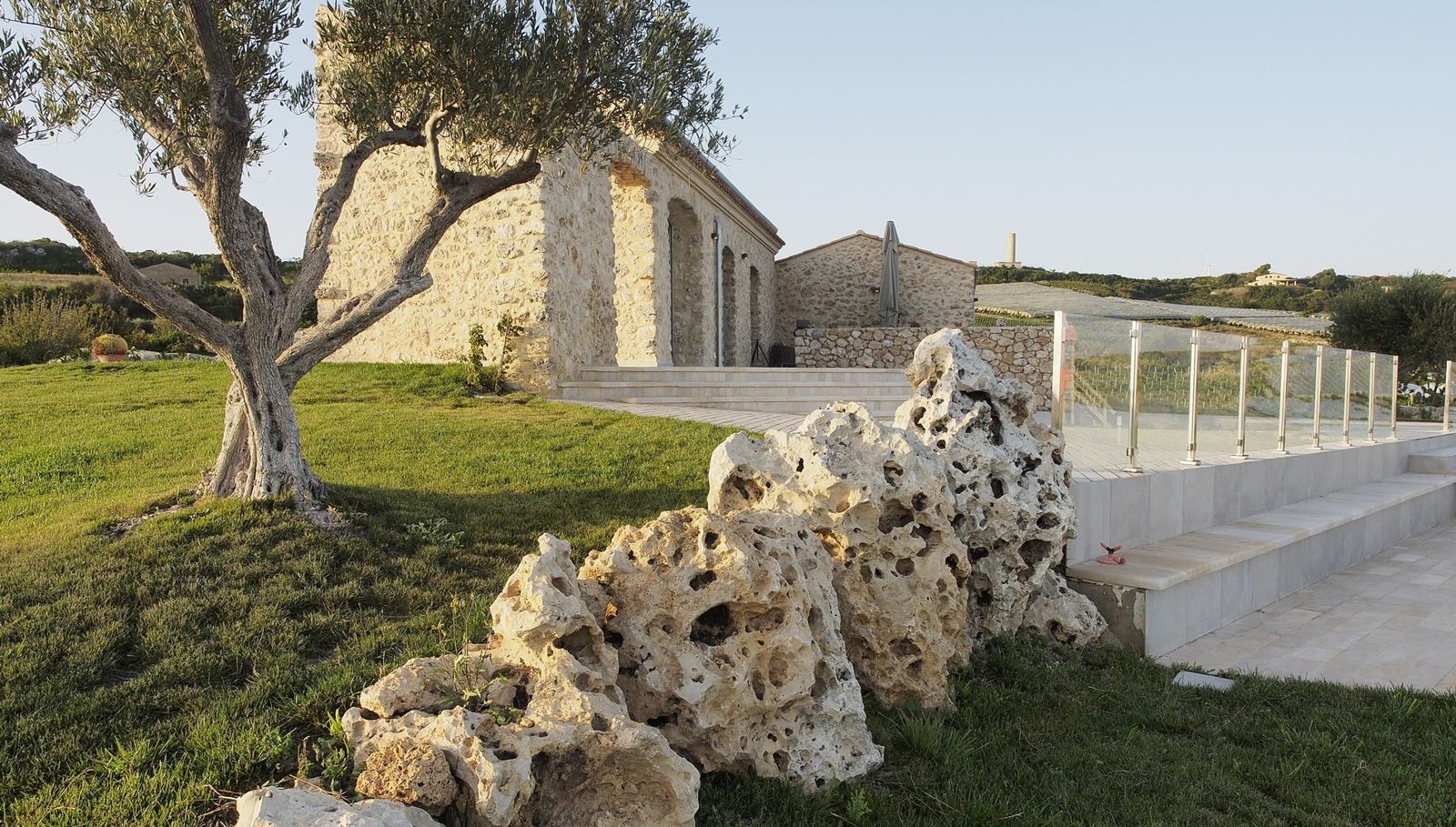 Ulivo e massi di roccia davanti al casale in pietra