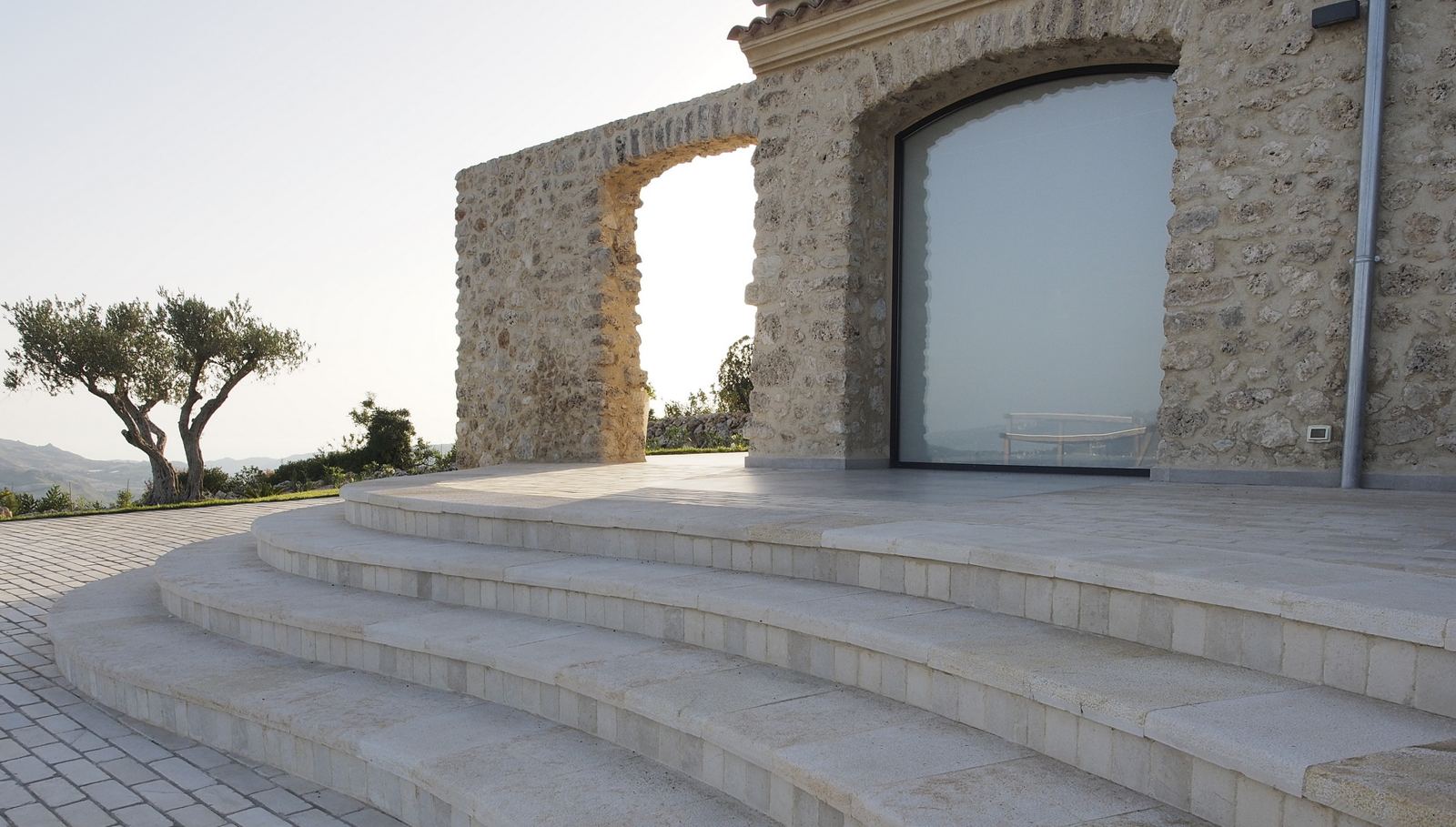 Scalinata curva in pietra e arco del casale